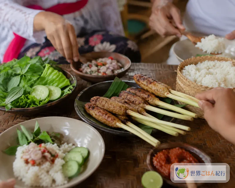 白いご飯、サンバル・マタ、青菜とサテ・リリットを囲むバリの家庭の食卓